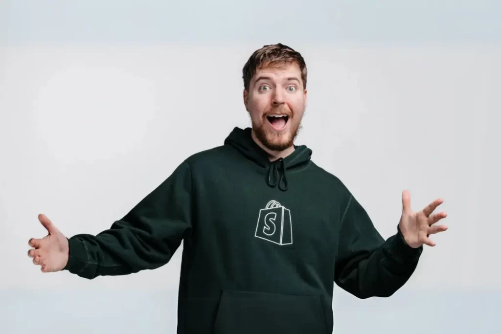 MrBeast em pé, confiante, com o logo dos Beast Games ao fundo, simbolizando o início da competição épica que promete entretenimento e a chance de mudança de vida com um prêmio de cinco milhões de dólares.